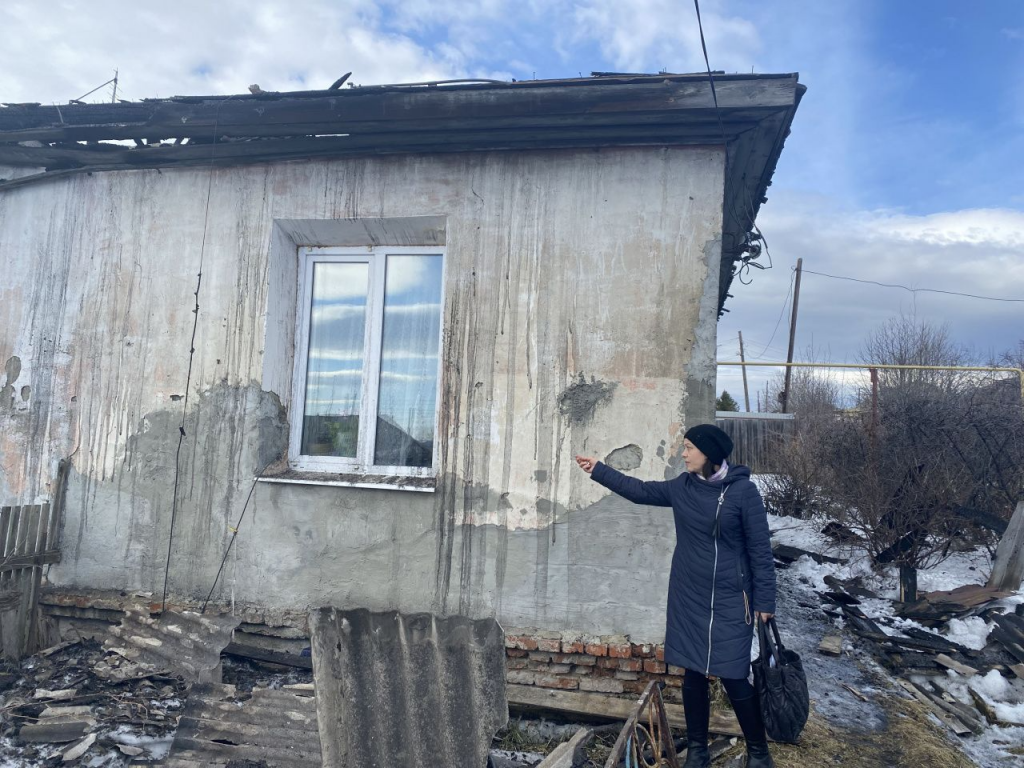 Надежда Россолова показывает на обгоревшую крышу дома. Фасад жители готовы сами привести в порядок. Фото: Анна Куприянова, "Глобус"
