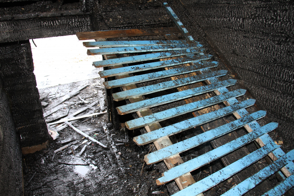 В подъезд занесли часть забора, чтобы пройти по сгоревшей лестнице. Фото: Константин Бобылев, "Глобус"