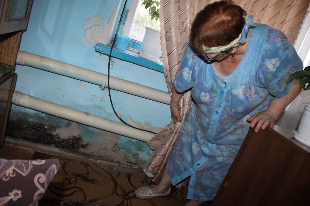 Галина Николаевна показывает, что в ее квартире по стенам ползет чернота. Фото: Мария Чекарова, "Глобус" 