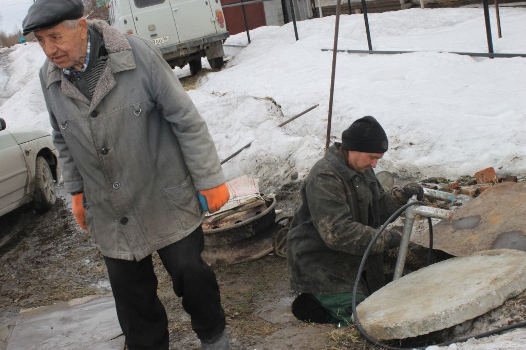 Владимир Дерябин лезет в колодец, чтобы проверить, как идет процесс отогрева водопровода. Фото: Мария Чекарова, "Глобус"