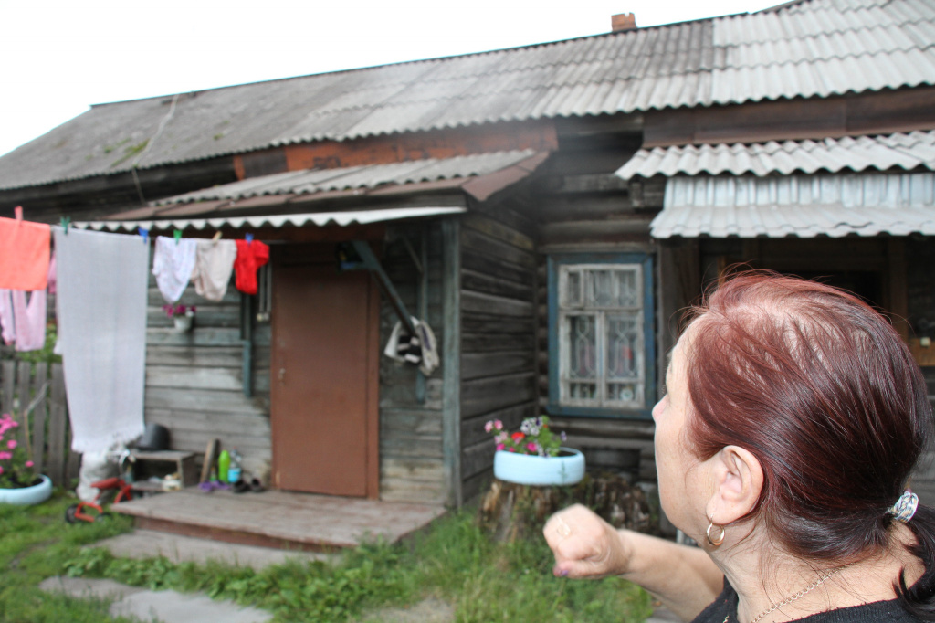 Василя показывает на очищенную от о мха часть крыши. Фото: Константин Бобылев, "Глобус"