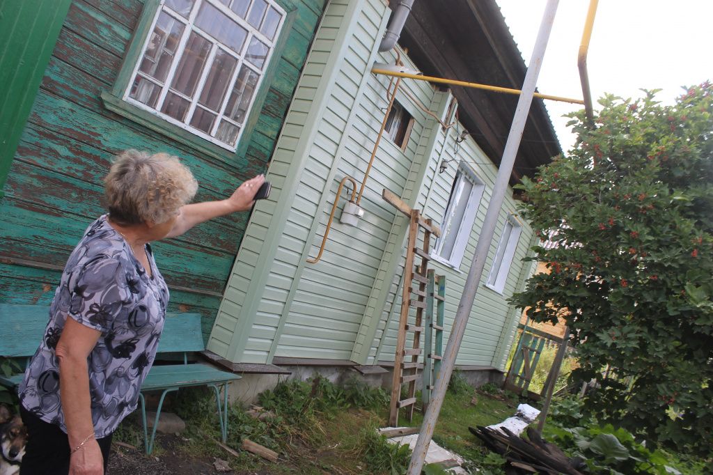 Антонина Михайловна показывает, что ей хотели обшить дом только сайдингом. Не сделав откосы, окна, водоотвод. Фото: Мария Чекарова, "Глобус"