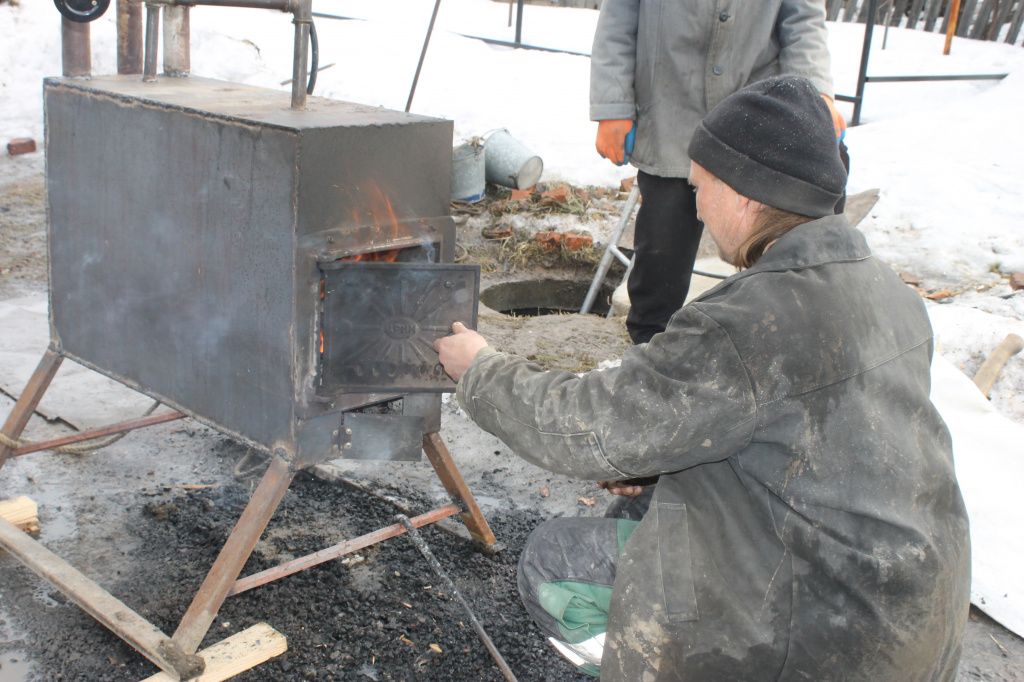 Владимир Дерябин помог соседям смастерить печь с баком для воды. Фото: Мария Чекарова, "Глобус"