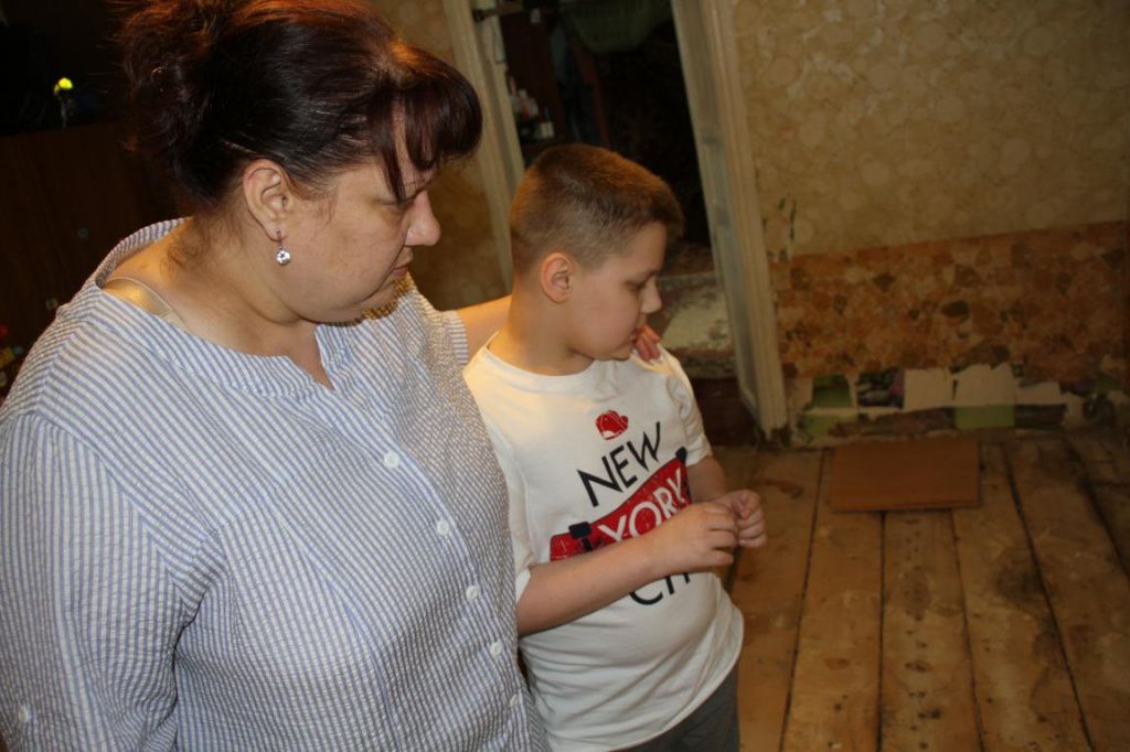 Оксана с сыном Никитой смотрят на сгнившие полы. Фото: Константин Бобылев, "Глобус"
