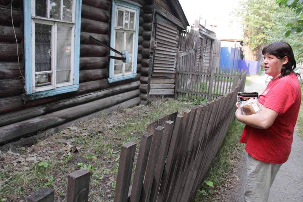 Юлия Киселева смотрит на мемориальную доску и говорит, что из-за нее жители дома вынуждены жить в ужасных условиях. Фото: Константин Бобылев, “Глобус”